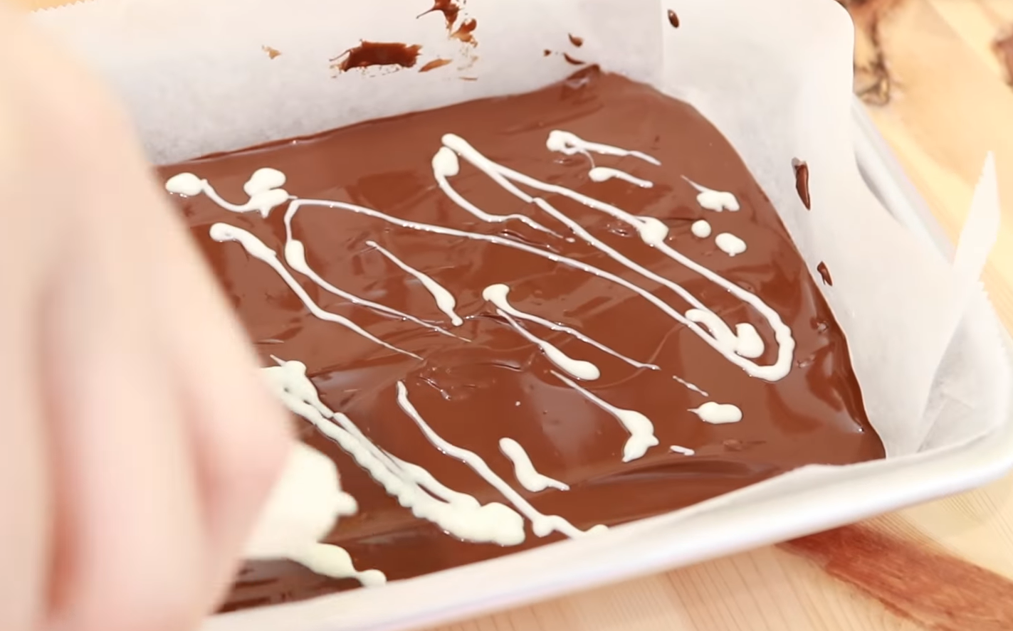 チョコが完全に溶けたら、クッキングシートを敷いたバットなどに流し入れ、ホワイトチョコペンで模様を付ける。