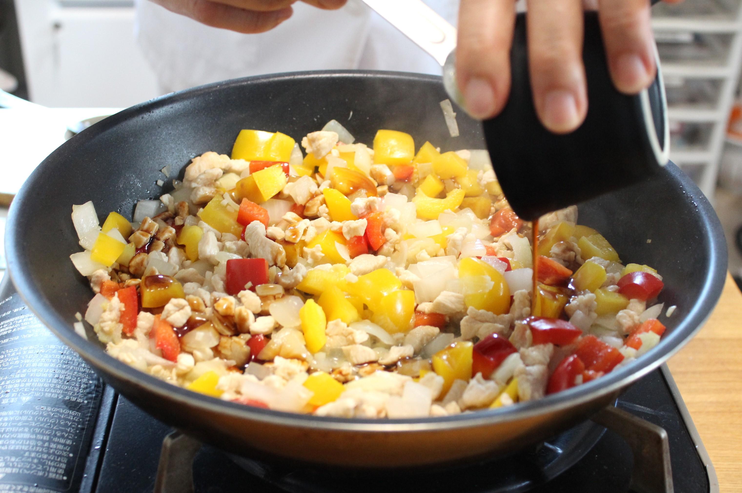 鶏肉の色が変わってきたらパプリカを加え、軽く炒めたら調味料を回しかける。
